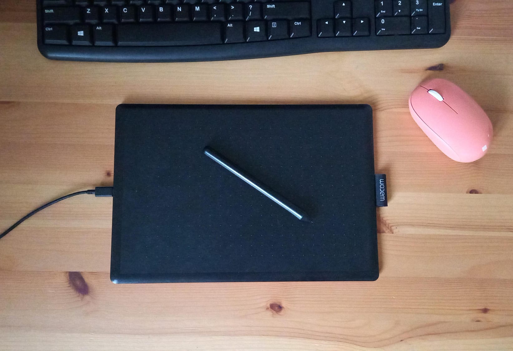 Escritorio minimalista con tableta gráfica, teclado y ratón en madera, concepto de productividad y software libre
