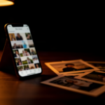 Fondo oscuro con un móvil mostrando una galería de fotos iluminado con luz cálida: portada del artículo sobre Immich